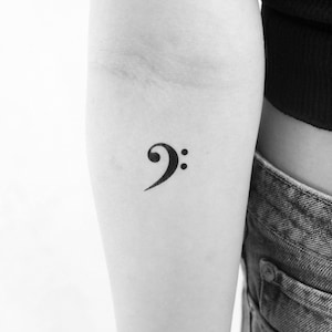 Op de afbeelding: Een zwarte basissleutel tattoo op de arm van een persoon.