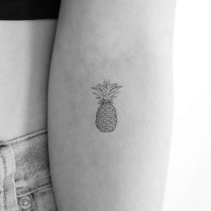 May include: A simple line drawing tattoo of a pineapple on a person's arm.