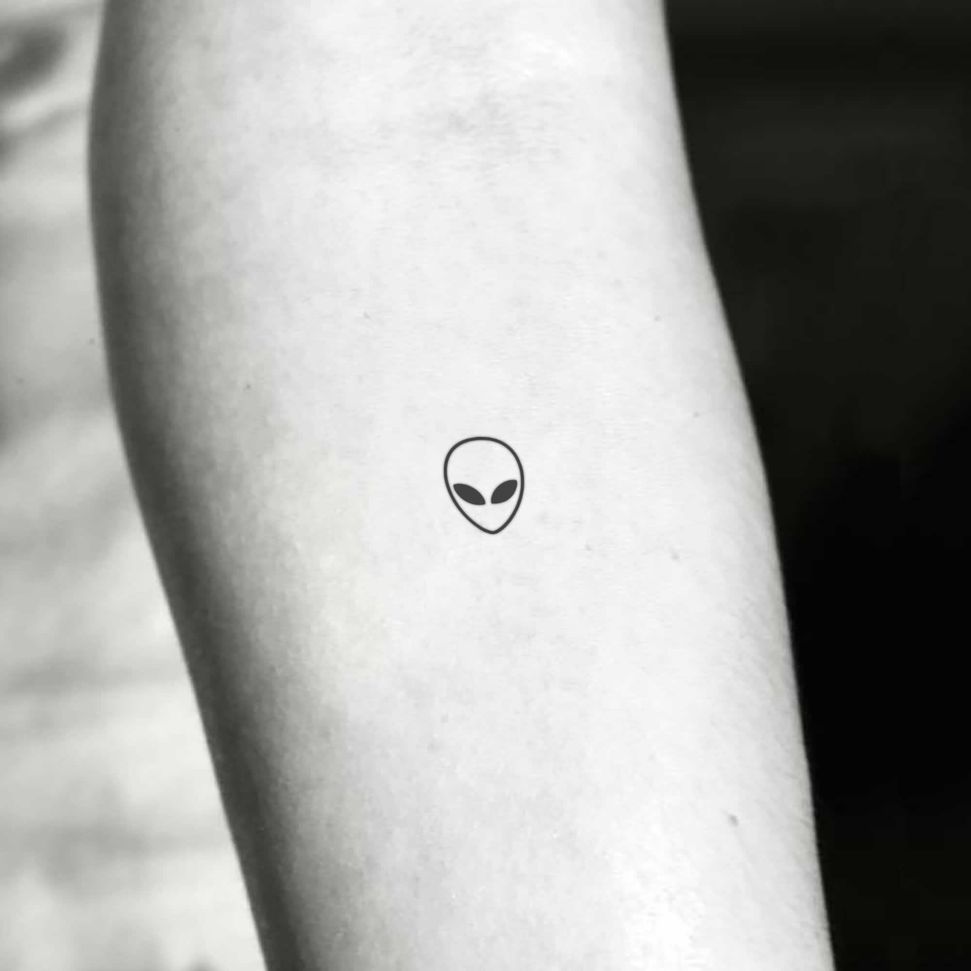 Minimalist alien head tattoo on the wrist