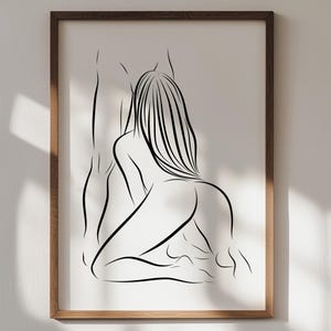 May include: A framed wall art print featuring a black line drawing on a white background. The illustration depicts the silhouettes of two figures in an intimate pose, with one figure kneeling and the other standing, rendered in simple, fluid lines.