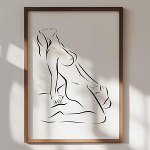 May include: A framed art print featuring a minimalist line drawing of a nude figure. The artwork is rendered in black lines on a white background, with a natural wood-tone frame. The figure is in a seated pose, with the head tilted back.