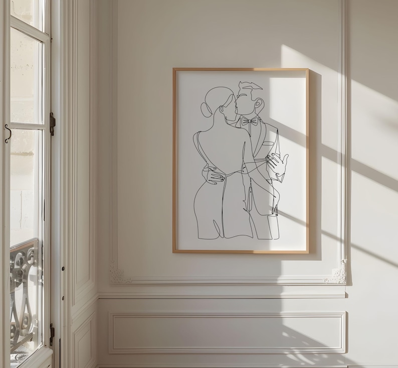 May include: A black and white line drawing of a couple embracing. The woman is wearing a dress and the man is wearing a suit. The drawing is framed in a light wood frame.