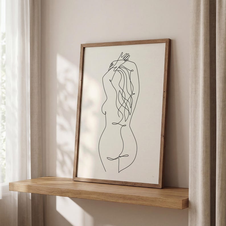 Puede incluir: Una impresi&oacute;n art&iacute;stica enmarcada con un dibujo lineal minimalista de la espalda de una persona. La obra de arte es una l&iacute;nea negra continua sobre un fondo blanquecino, con un marco de madera natural. La impresi&oacute;n se exhibe en una estanter&iacute;a de madera.
