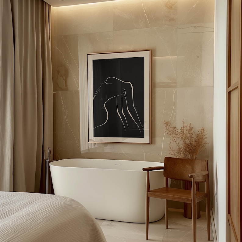 May include: A white bathtub with a black line abstract art print hanging above it. The bathtub is in a modern bathroom with beige tile walls and a wooden chair.