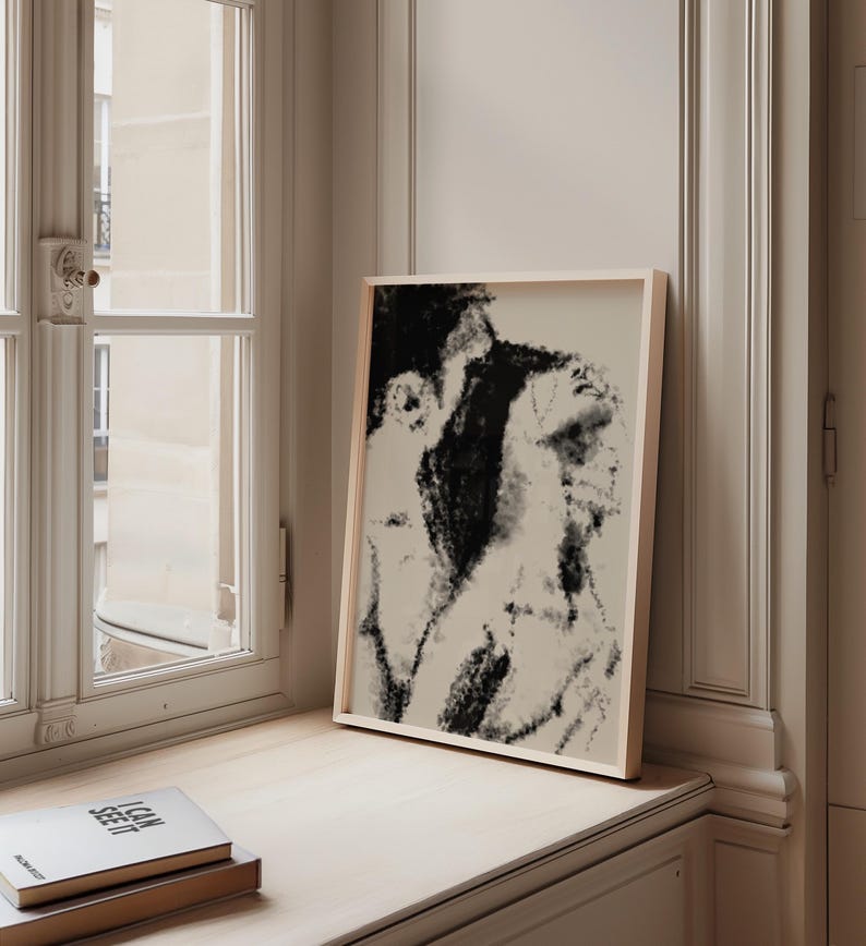 Puede incluir: Una impresi&oacute;n art&iacute;stica abstracta en blanco y negro enmarcada. La obra de arte presenta una representaci&oacute;n similar al carboncillo de dos figuras. El marco es de color claro y la impresi&oacute;n se exhibe en un alf&eacute;izar junto a una pila de libros. El texto "I CAN SEE IT" es visible.