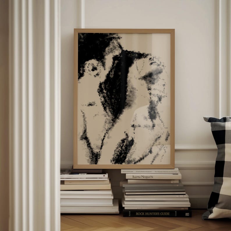 Puede incluir: Una impresi&oacute;n art&iacute;stica enmarcada con un boceto en blanco y negro de dos figuras. La obra de arte tiene un fondo neutro y est&aacute; enmarcada en un marco de madera marr&oacute;n claro. La impresi&oacute;n descansa sobre una pila de libros.