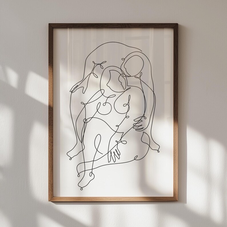 May include: A framed art print featuring a minimalist line drawing of two figures embracing. The artwork is rendered in black lines on a white background, encased in a brown wooden frame. The piece evokes themes of connection and intimacy.