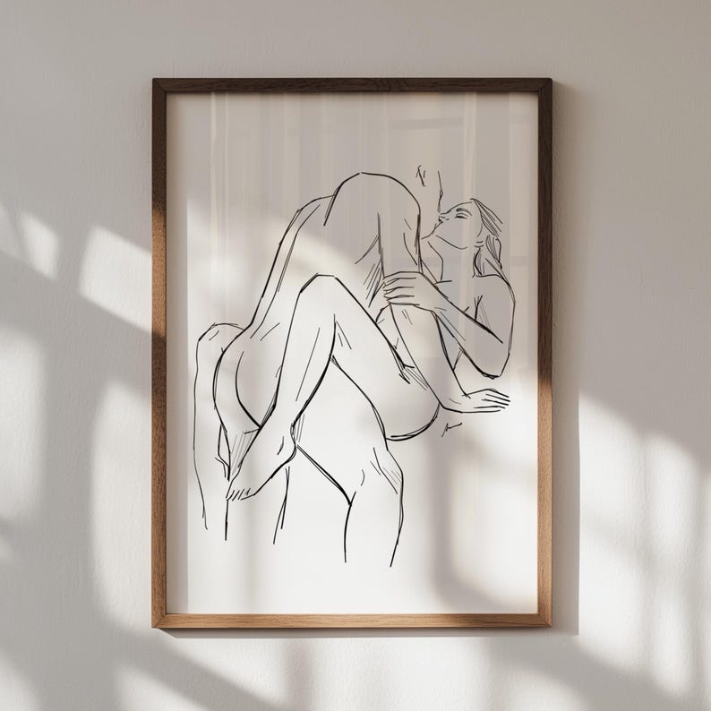 May include: A framed black and white line art print depicting an intimate embrace. The artwork features two figures in a passionate pose, with a minimalist style. The frame is a warm brown color, adding a touch of elegance to the piece.