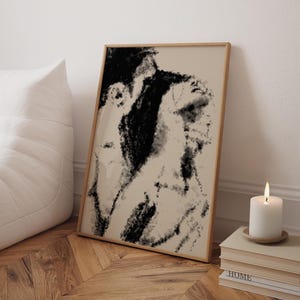 Puede incluir: Impresi&oacute;n art&iacute;stica abstracta en un marco de madera. La obra presenta una paleta de colores en negro y beige, con una textura similar al carboncillo. Una vela blanca est&aacute; sobre una pila de libros, junto a un coj&iacute;n blanco.