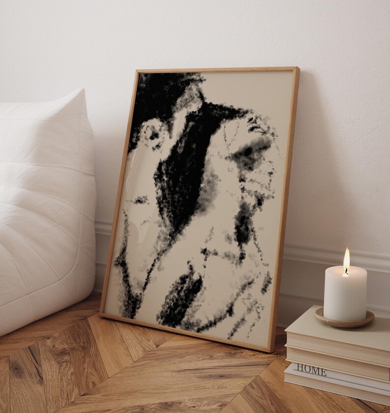 Puede incluir: Impresi&oacute;n art&iacute;stica abstracta en un marco de madera. La obra presenta una paleta de colores en negro y beige, con una textura similar al carboncillo. Una vela blanca est&aacute; sobre una pila de libros, junto a un coj&iacute;n blanco.