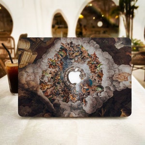 Può includere: Custodia per laptop con un design a affresco rinascimentale di figure in un cielo nuvoloso. Il logo Apple è visibile. La custodia è su un tavolo bianco accanto a un bicchiere di caffè freddo.