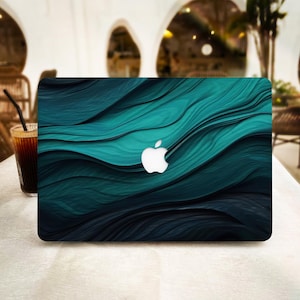 Può includere: Una skin per laptop con un motivo astratto e fluido di onde in tonalità blu ottanio, turchese e blu navy scuro. Il design copre il coperchio esterno del laptop, mostrando un logo Apple bianco ritagliato al centro della texture a strati.