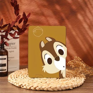 May include: A brown and yellow book cover with a cartoon image of a chipmunk looking up at an acorn. The chipmunk has brown fur, a white belly, and big brown eyes.