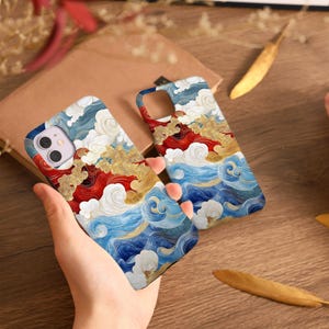May include: Two phone cases with a vibrant design featuring swirling blue waves, red accents, and gold highlights. The cases have a glossy finish and a protective bumper. The design evokes a sense of movement and artistic flair.