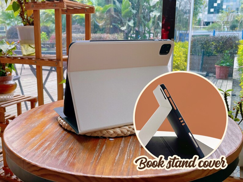 May include: A white and black tablet case with a stand feature. The case is folded to create a stand for the tablet. The text "Book stand cover" is visible in the image.