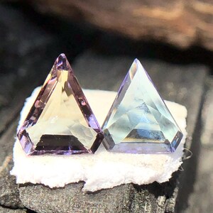 May include: Two faceted gemstones, one is a light purple and yellow, the other is a light blue and purple.