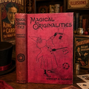 May include: A red hardcover book titled Magical Originalities by Ernest E. Noakes. The front cover features a black line drawing of a bearded figure in a robe and pointed hat performing magic with a top hat, dice, and a tambourine.