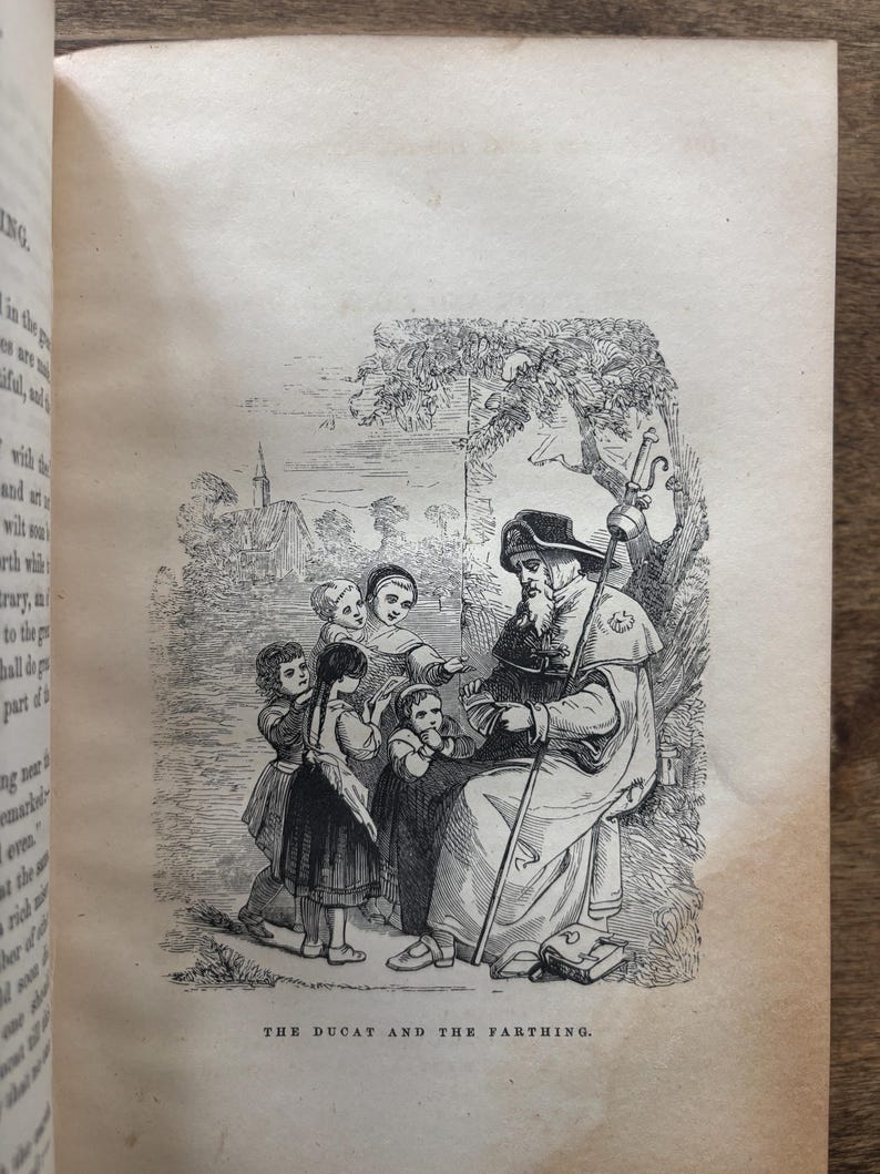 May include: An antique black and white illustration from a book depicts a robed figure with a staff, seated under a tree, surrounded by children. The text at the bottom reads "THE DUCAT AND THE FARTHING."