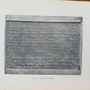 May include: A monochrome image of a slate chalkboard with handwritten text in white chalk. The chalkboard is framed with a wooden border. The text is a handwritten letter. The bottom of the image has the text "FIG. G - SLATE WRITING."