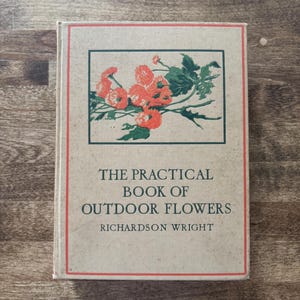 May include: A hardcover book titled The Practical Book of Outdoor Flowers by Richardson Wright. The beige cover features a rectangular illustration of orange flowers with green leaves, enclosed by a thin red border line on the front panel.