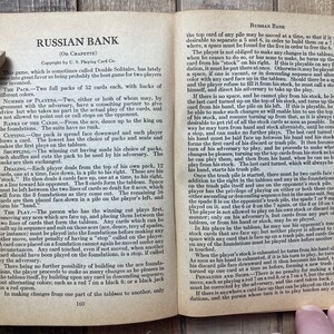Puede incluir: Un libro antiguo con una ilustraci&oacute;n en blanco y negro de un juego de cartas llamado Russian Bank. El libro est&aacute; abierto en una p&aacute;gina con instrucciones sobre c&oacute;mo jugar al juego.