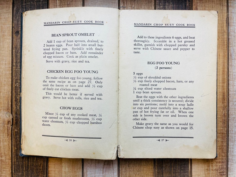 Pu&ograve; includere: Pagine aperte di un libro di cucina con ricette di Mandarin Chop Suey. La pagina sinistra presenta le ricette per Omelette di germogli di fagioli, Chicken Egg Foo Young e Chow Eggs. La pagina destra ha le istruzioni per Egg Foo Young.