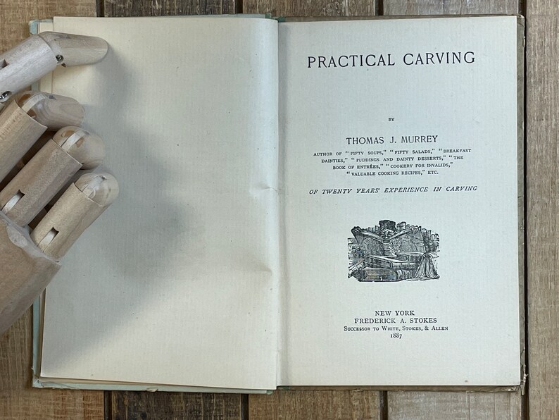 Pode incluir: Um livro antigo intitulado "Practical Carving" de Thomas J. Murrey. A capa do livro apresenta uma ilustra&ccedil;&atilde;o em preto e branco de uma pessoa a esculpir um assado.