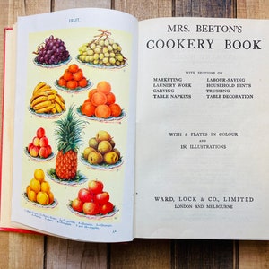Pode incluir: Um livro de cozinha vintage aberto intitulado "Mrs. Beeton's Cookery Book" com se&ccedil;&otilde;es sobre marketing, trabalho de lavanderia, talha, guardanapos de mesa, economia de trabalho, dicas para o lar, amarra&ccedil;&atilde;o e decora&ccedil;&atilde;o de mesa. O livro apresenta 8 placas em cores e 150 ilustra&ccedil;&otilde;es. A capa mostra uma ilustra&ccedil;&atilde;o colorida de v&aacute;rias frutas, incluindo uvas, bananas, laranjas, ma&ccedil;&atilde;s e um abacaxi.