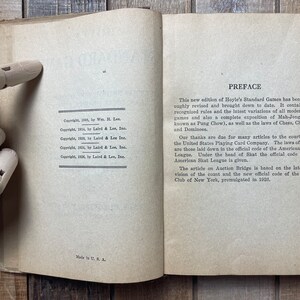Puede incluir: Un primer plano de la p&aacute;gina de prefacio de un libro con el t&iacute;tulo "Prefacio" y texto que describe el contenido y las revisiones del libro. El texto menciona la inclusi&oacute;n en el libro de reglas para varios juegos de cartas, incluyendo Mah-Jong, ajedrez, damas y domin&oacute;. El texto tambi&eacute;n reconoce las contribuciones de United States Playing Card Company y la American Whist League.