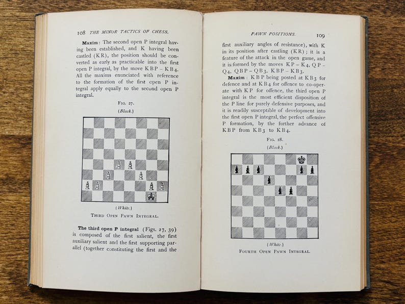 May include: Open book with text and chess diagrams. The left page features a diagram labeled "Third Open Pawn Integral." The right page shows a diagram labeled "Fourth Open Pawn Integral." The book is open on a wooden surface.