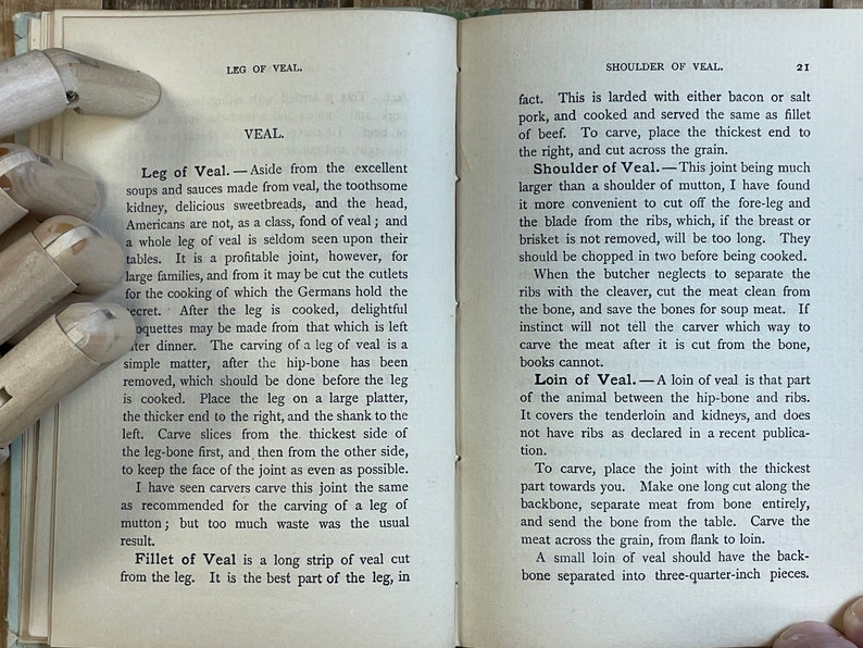 Pode incluir: Uma p&aacute;gina de livro vintage com texto sobre diferentes cortes de vitela, incluindo perna, ombro e lombo. O texto descreve como cortar cada corte e fornece dicas para cozinhar.