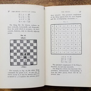 May include: Open book with pages displaying chess diagrams and text. The left page features a black and white chessboard diagram with arrows. The right page shows a grid of numbers. The book is open on a wooden surface.