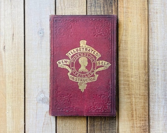 May include: A red, leather-bound book with gold lettering and a gold embossed image of a head with the text "Illustrated Phrenology, New Physiology, Self Instructor".