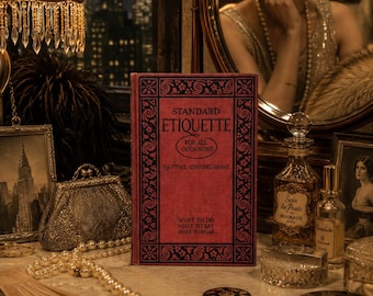 Peut inclure: Une scène de coiffeuse vintage avec un livre rouge intitulé "Standard Etiquette" avec des bordures décoratives noires. D'autres articles incluent un collier de perles, des flacons de parfum, un petit sac à main et un miroir reflétant une femme. La scène se déroule dans une pièce avec vue sur la ville.