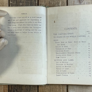 Pode incluir: Um livro antigo com capa branca e texto preto. O t&iacute;tulo do livro &eacute; "The Carving-Knife" e o conte&uacute;do inclui uma lista de diferentes cortes de carne, como carne bovina, carneiro e cordeiro.
