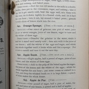 May include: Open book page with text from a vintage cookbook. The page features recipes for desserts like Rice and Pears, Orange Sponge, Apple Snow, and Apple de Par. The text is in black ink.