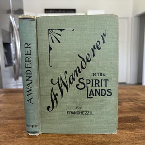 May include: An antique book titled "A Wanderer in the Spirit Lands" by Franchezzo. The book has a light green cover with black lettering and a decorative sunburst design. The spine reads "A Wanderer".