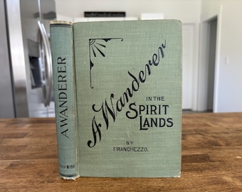 May include: An antique book titled "A Wanderer in the Spirit Lands" by Franchezzo. The book has a light green cover with black lettering and a decorative sunburst design. The spine reads "A Wanderer".