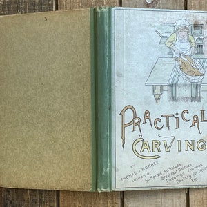 Pode incluir: Um livro vintage intitulado "Practical Carving" de Thomas J. Murrey, autor de "50 Soups, 50 Salads". A capa apresenta um desenho de linha de uma pessoa cortando um peru em uma mesa.