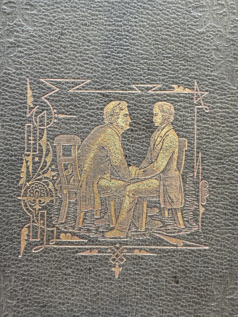 Puede incluir: Primer plano de una portada de libro con un fondo verde oscuro texturizado. Una ilustraci&oacute;n dorada representa dos figuras sentadas tomadas de la mano, enmarcadas por l&iacute;neas y formas decorativas. Las figuras visten ropa de &eacute;poca.