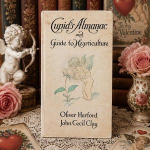 May include: A vintage hardcover book titled Cupid's Almanac and Guide to Hearticulture by Oliver Herford and John Cecil Clay. The off-white cover features a delicate illustration of a winged cherub smelling a flower in soft green and tan tones.