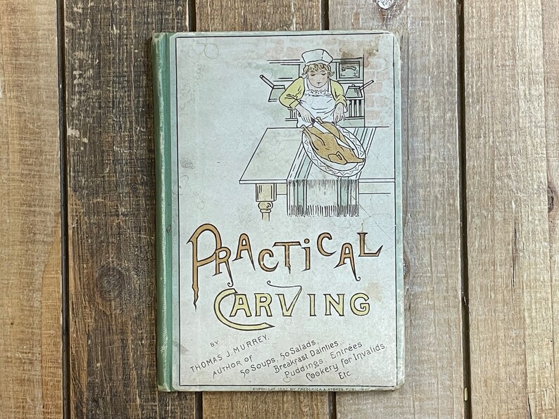 Pode incluir: Um livro vintage intitulado "Practical Carving" de Thomas J. Murrey, autor de "50 Soups, 50 Salads, Breakfast Dainties, Puddings, Entrees, Cookery for Invalids, Etc.". A capa apresenta um desenho de linha de uma pessoa cortando um peru.