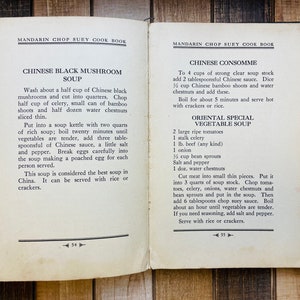 Pu&ograve; includere: Pagine di un libro di cucina aperto con ricette di zuppe cinesi. La pagina sinistra presenta la Zuppa di Funghi Neri Cinese, mentre la destra offre Consomm&eacute; Cinese e Zuppa di Verdure Speciale Orientale. Su una superficie di legno.