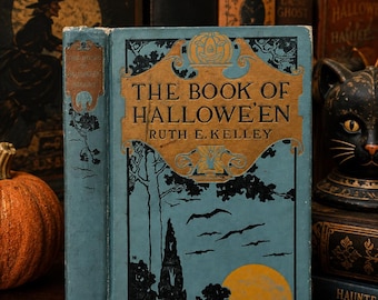 以下が含まれることがあります： ルース・E・ケリー著『The Book of Hallowe'en』というタイトルのヴィンテージのハードカバー本。表紙は水色で、中央の金色のパネルにはカボチャのイラスト、木々の黒いシルエット、飛んでいるコウモリ、そして大きな黄色い月が描かれています。