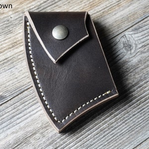 May include: Dark brown leather axe sheath with a snap closure and white stitching.