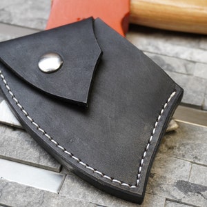 May include: A black leather axe sheath with white stitching and a silver snap closure.