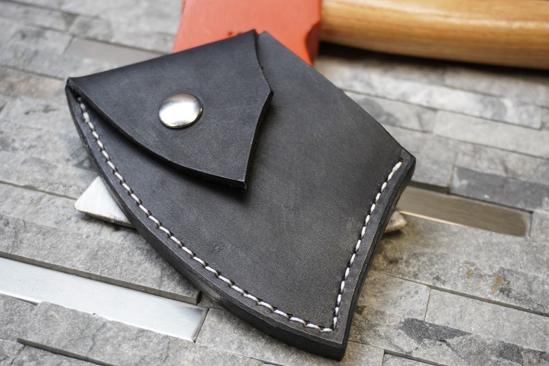 May include: A black leather axe sheath with white stitching and a silver snap closure.