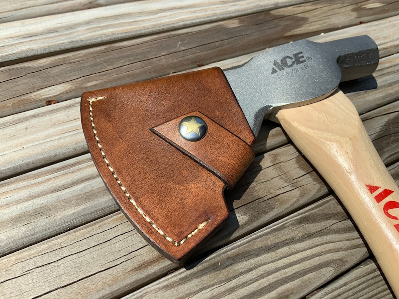 Pu&ograve; includere: Ascia con manico in legno e testa in metallo, con la scritta "ACE". L'ascia ha un fodero in pelle marrone fissato con un bottone a forma di stella. L'ascia &egrave; progettata per l'uso all'aperto.
