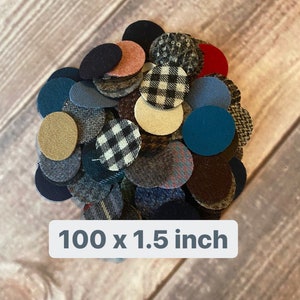 Può includere: Una collezione di 100 cerchi di tessuto, ognuno con un diametro di 3,8 cm. I cerchi sono realizzati in vari tessuti a fantasia, tra cui scozzese, tweed e colori solidi. I cerchi sono disposti in una pila su una superficie di legno.