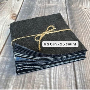 May include: A stack of 25 black fabric squares, each measuring 6 inches by 6 inches, tied together with twine. The squares are arranged in a neat pile, with the top square visible. The text "6 x 6 in - 25 count" is printed on the top square.